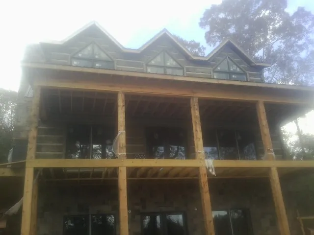 Dormers and porch framing on a large log home under construction — Roof Coating work by our crew in Shamokin Dam