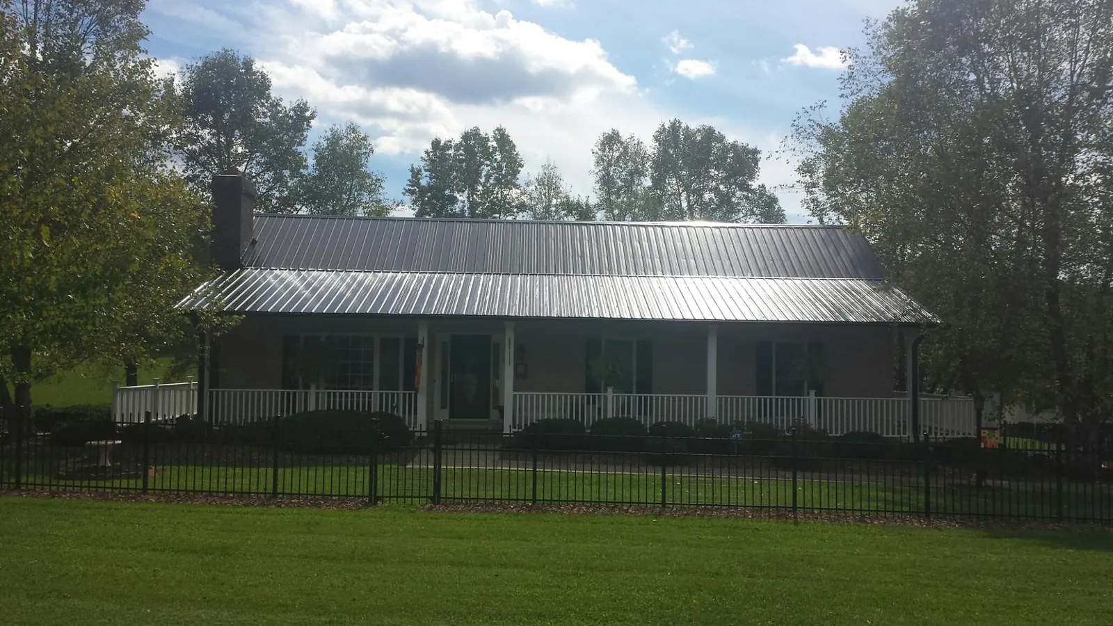 Gray metal roof on a brick ranch with a full width front porch — Gutter Guard Installation work by our crew in Shamokin Dam