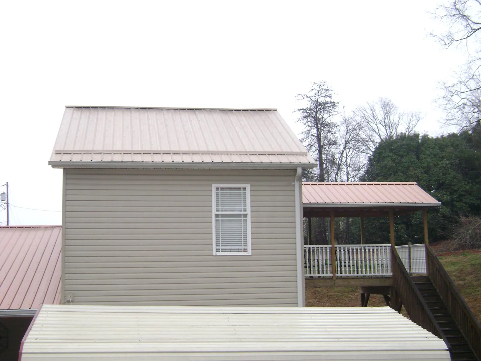 Tan metal roofs on a two story addition and attached porch, from a Roof Replacement job in Shamokin Dam