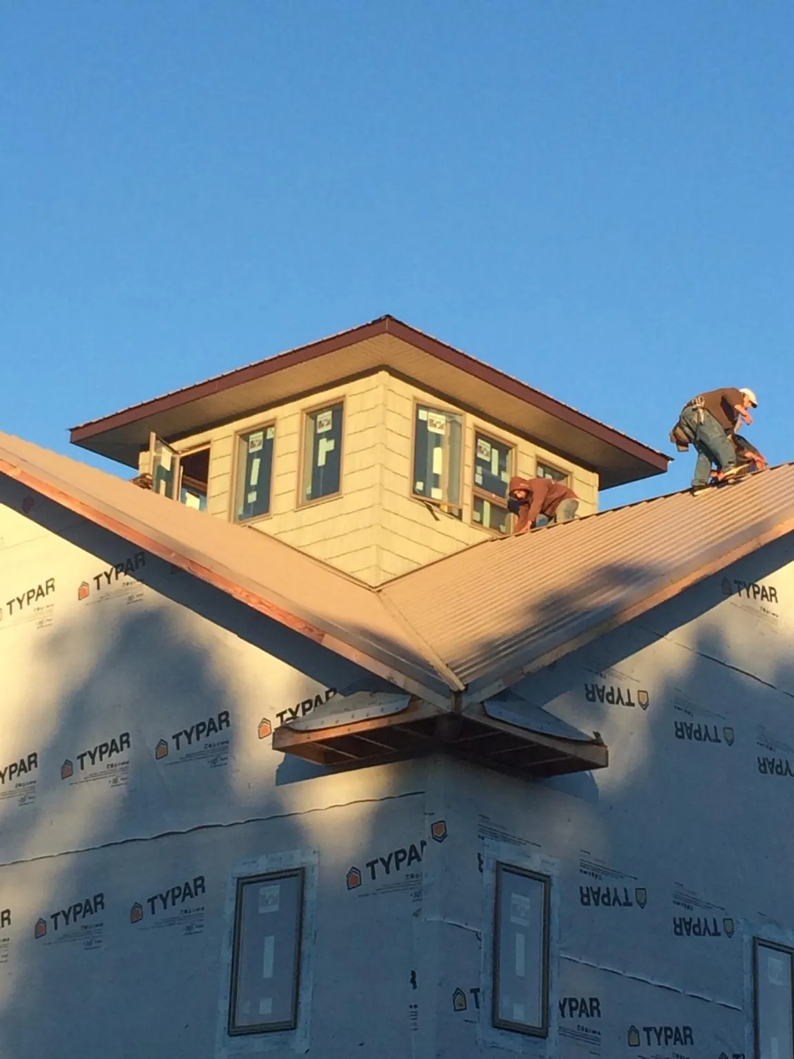Roofers working around a rooftop cupola on a new metal roof at sunset — Roof Waterproofing in Shamokin Dam by Roofing Brothers